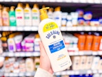 hand holding a bottle of gold bond lotion in walmart aisle