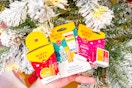 person holding burt's bees gift sets in front of a christmas tree