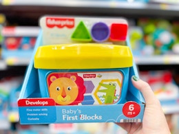 hand holding out fisher price toy in the aisle at Walmart