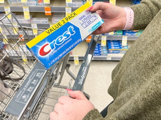 woman holding crest toothpaste near walgreens cart