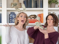 Two women excitedly throwing cash in the air