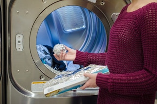 someone putting aluminum foil ball in dryer