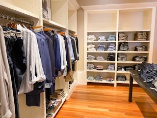 button up shirts on shelf in the foreground, and dress pants and shirts hung up on racks to the right in banana republic