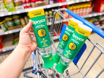 hand holding a bottle of spruce grass and weed killer with two in walmart cart