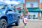 a woman walking to her car with a walgreens bag 