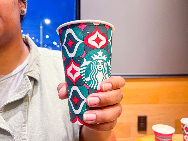 a person holding a startbucks holiday drink