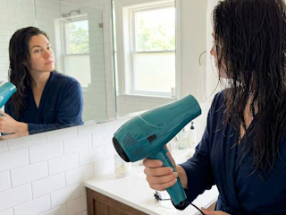 a woman blow drying her hair