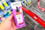 person holding a truskin facial serum over a cvs cart