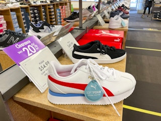 A row of shoes for sale with a purple sign next to one of them that says "Clearance, 20% off"