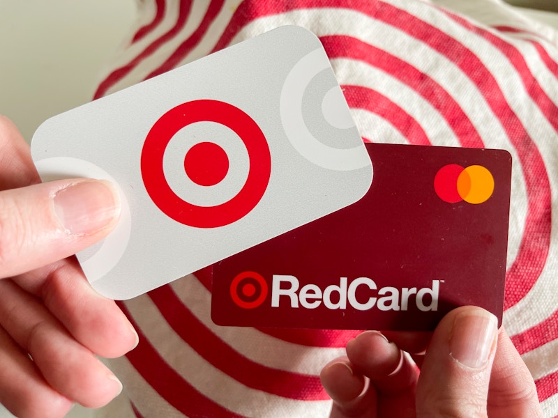 A person's hands, one holding a Target gift card, and the other holding a Target RedCard, in front of a Target bag.