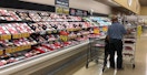 a person looking at pre packed meat on a supermarket shelf