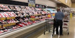 a person looking at pre packed meat on a supermarket shelf