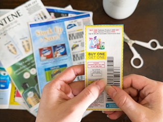 Someone holding a Buy one get one free coupon cut out of a newspaper