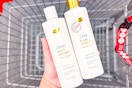 person holding 2 bottles of dove shampoo over a cart