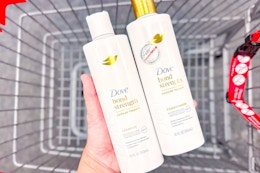 person holding 2 bottles of dove shampoo over a cart