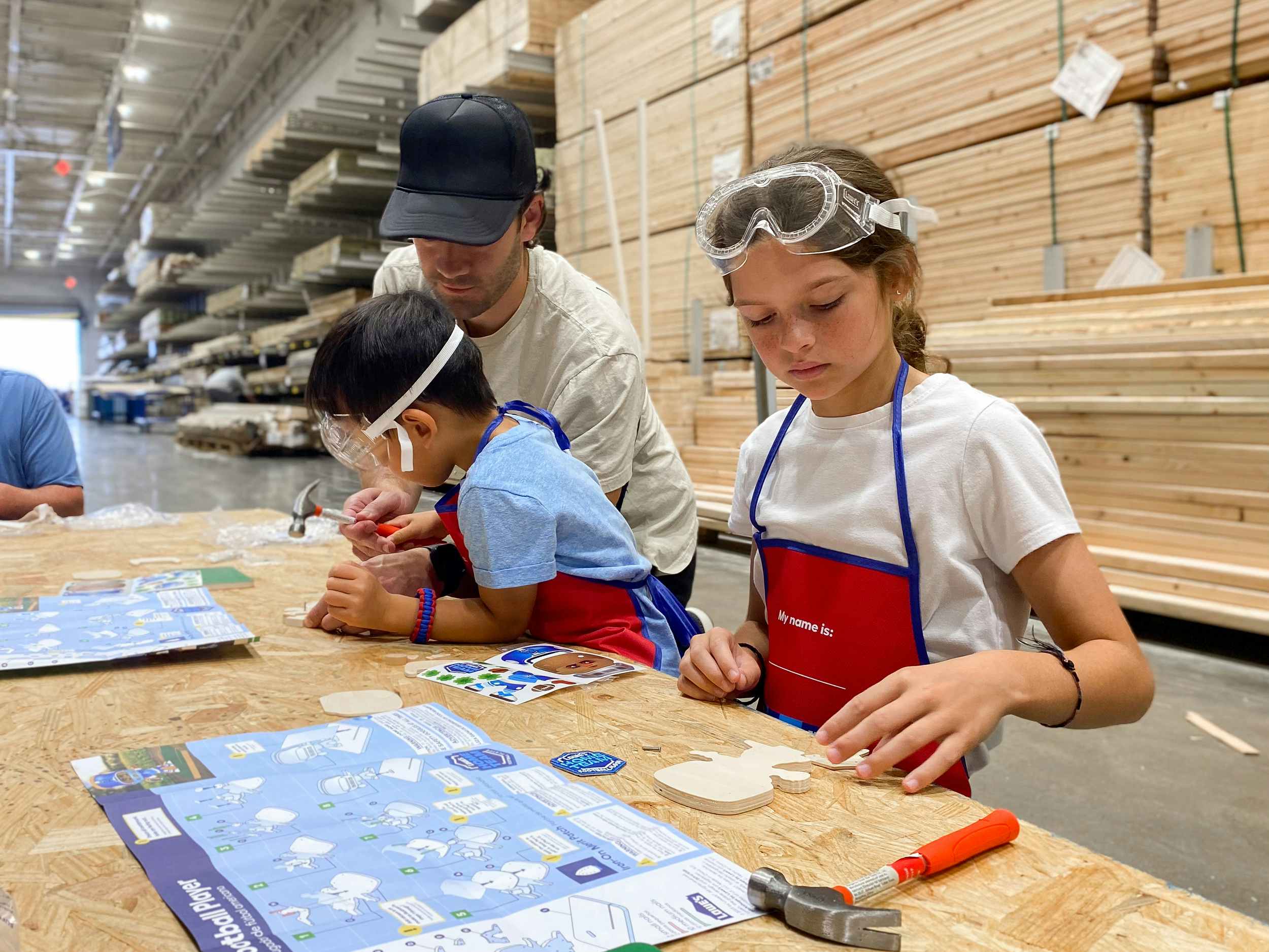 father and children working on football player craft at lowe's diy-u free kids workshop