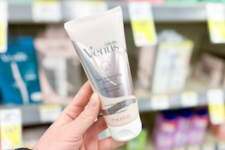 person holding a bottle of venus shaving exfoliant