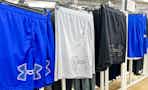 under armour shorts hanging on hangers in a department store