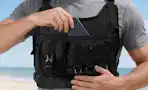 man placing phone into black weighted vest