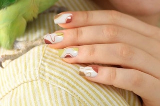 a hand resting on a shoulder with neutral earthy design on the nails