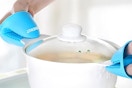person holding pot with oven mitts