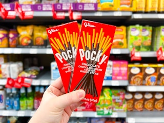 hand holding two pocky biscuit sticks in walmart aisle