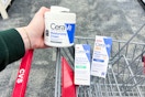 person holding cerave moisturizing cream over a cart with other cerave skincare products in it