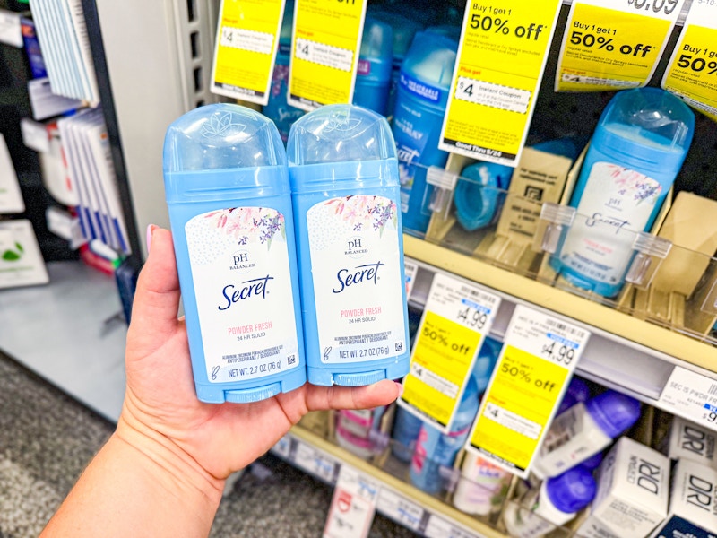 person holding 2 secret deodorants by the display