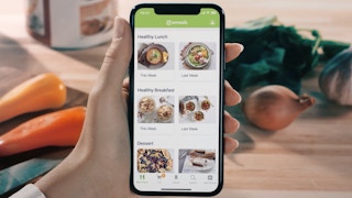 person holding phone with e meals app on it
