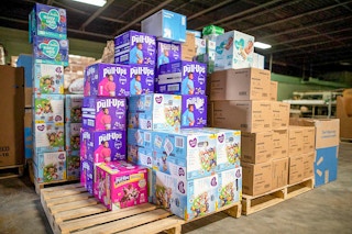 A large stack of diapers on pallets inside a warehouse.