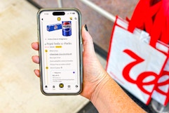 hand holding smartphone with kcl app 1-clip coupons next to a walgreens shopping bag