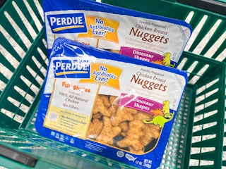 Two packages of Perdue dinosaur-shaped chicken nuggets sitting in a Publix hand basket.