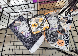 a cart with halloween themed kitchen towels, pot holders, and oven mitts