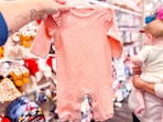 hand holding a carter's baby romper at target