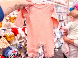 hand holding a carter's baby romper at target