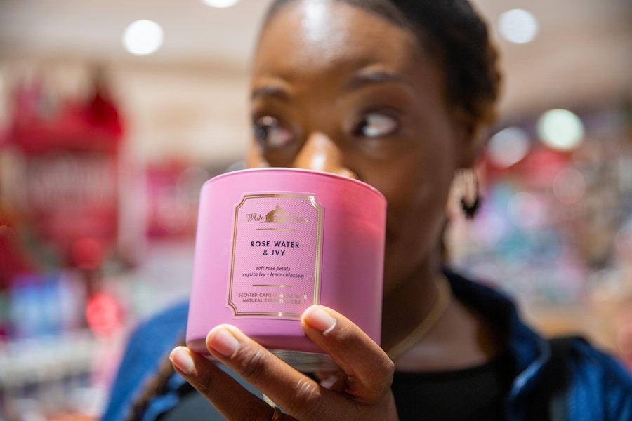 Person holding up a pink candle from Bath and Body works to their nose to smell