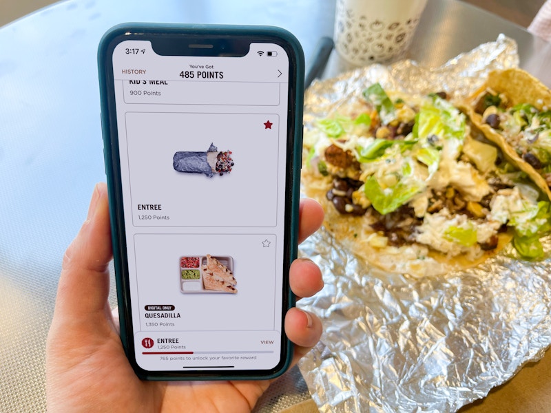 someone holding phone with chipotle app next to burrito bowl