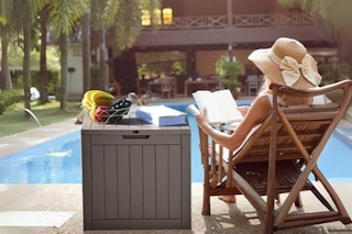 Woman sitting next to an outdoor storage box.