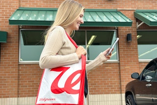 a woman looking at a cell phone outside of walgreens 