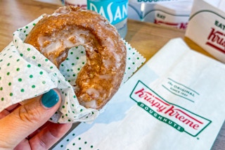someone holding a pumpkin spice cake donut from krispy kreme