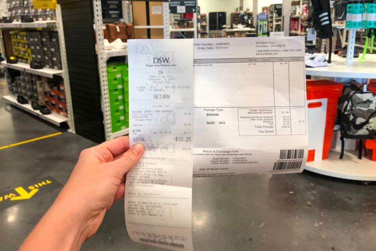 Hand holding up DSW return receipt in DSW store