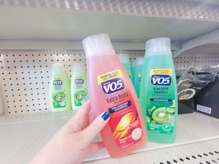 hand holding a bottle of vo5 shampoo by another bottle