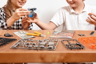 two kids building a robot at a table