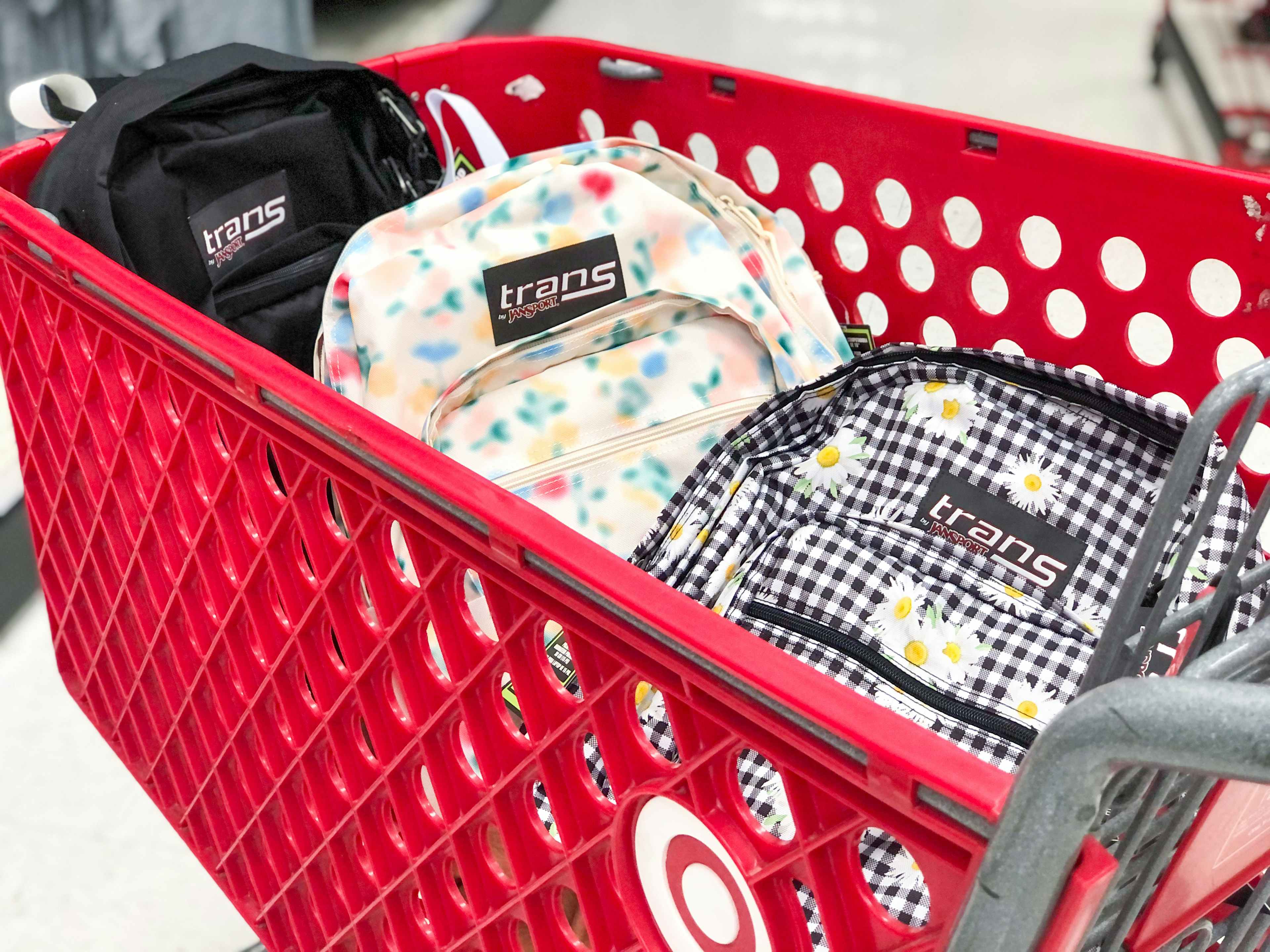 Three Trans Jansport backpacks in a shopping cart at Target.