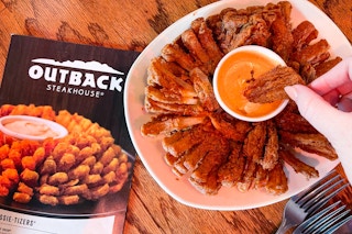 A mom and her child holding Burger King cups and to-go bags while standing in front of a Burger King restaurant.