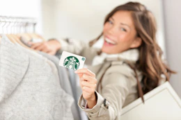 A woman holds up a starbucks gift card