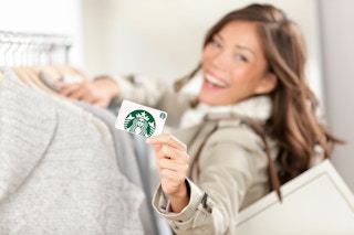 A woman holds up a starbucks gift card