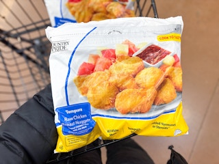 hand holding a bag of country pride tempura chicken nuggets