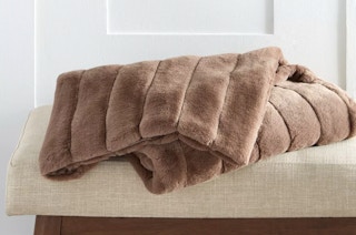a brown oversized faux fur throw on a bench
