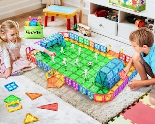 two kids building a sports field with colorful tiles in a room